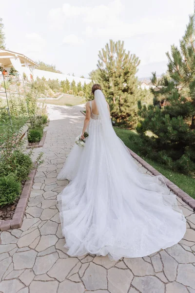 Arkadan bir fotoğraf. Beyaz gelinlikli güzel bir kadın sıcak bir düğün gününde gülümsüyor.