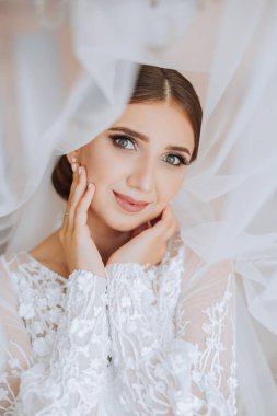 Beyaz gelinlik içinde duvak tutan genç bir gelin otel odasında esmer gelin portresi, düğünden önceki sabah..