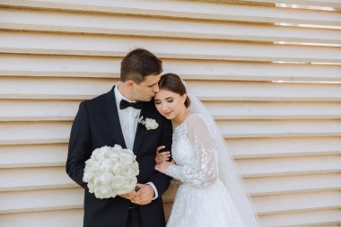 Gelin ve damat kucaklaşır. Gelin damadı nazikçe omuzlarından kucaklıyor. Güzel bir düğün çifti. Yeni evlilerin ilişkilerinde romantizm kavramı. Balayı.