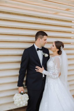 Gelin ve damat kucaklaşır. Gelin damadı nazikçe omuzlarından kucaklıyor. Güzel bir düğün çifti. Yeni evlilerin ilişkilerinde romantizm kavramı. Balayı.