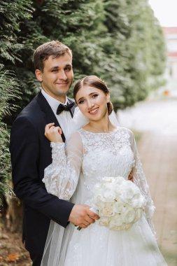 Mutlu çift dışarıda düğünlerini kutluyor. İnanılmaz gülümseyen bir düğün çifti. Güzel gelin ve şık damat. Düğün portresi.