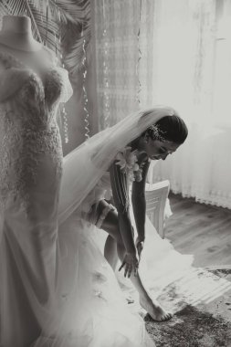 Odasında uzun peçeli, bornoz giymiş güzel bir gelin. Bir mankenin üzerinde gelinlik. Düğün töreninden önceki sabah gelin..