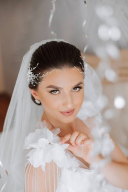 Düğün töreninden önce sabahları sabahlık giymiş güzel bir gelin. Gelinin saç stili inanılmaz. Doğal ve modern makyaj. Sabahlık giymiş genç bir gelinin portresi.