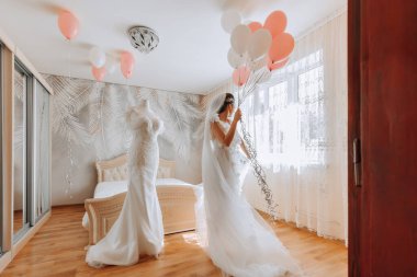 Odasında uzun peçeli, bornoz giymiş güzel bir gelin. Bir mankenin üzerinde gelinlik. Düğün töreninden önceki sabah gelin..