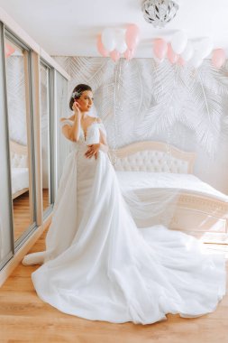 Uzun gelinlik ve duvak giymiş genç esmer otel odasında. Büyüleyici bir gelin, uzun boylu, muhteşem beyaz elbisesiyle düğünden önceki sabah.