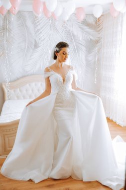 Uzun gelinlik ve duvak giymiş genç esmer otel odasında. Büyüleyici bir gelin, uzun boylu, muhteşem beyaz elbisesiyle düğünden önceki sabah.
