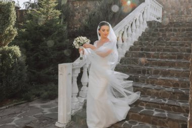 Beyaz gelinlik içinde güzel bir gelin. Genç bir gelin kız bir yaz günü doğada yürüyor. Yaz düğünü.