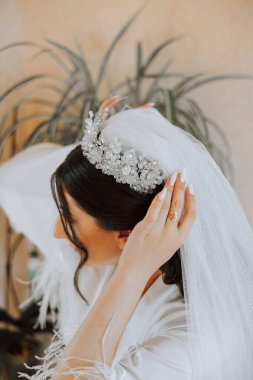 Arkadan yakın çekim görüntüsü. Gelinin saçında bir diyadem. Düğün mücevheri konsepti. Gelin düğün için hazırlanıyor..