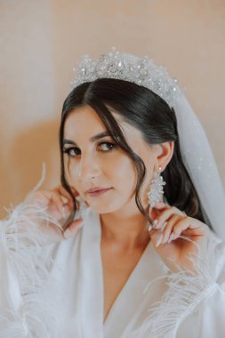 Düğün töreninden önce sabahları sabahlık giymiş güzel bir gelin. Gelinin saç stili inanılmaz. Doğal ve modern makyaj. Sabahlık giymiş genç bir gelinin portresi.