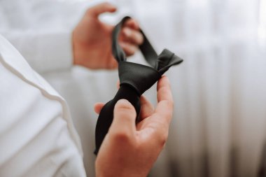 Beyaz gömlekli sakallı bir adam kravatını düzeltiyor. Damat sabahı. Yakın çekim, düğün ya da önemli bir toplantı için erkek kravatı..