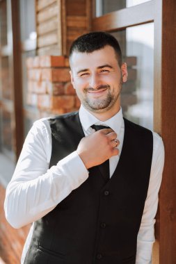 Yazın doğadaki damadın portresi. Zarif bir siyah iş elbisesi içinde şık, uzun bir damat. Doğada bir iş adamı. Başarılı bir adamın portresi. Damadın düğün portresi.