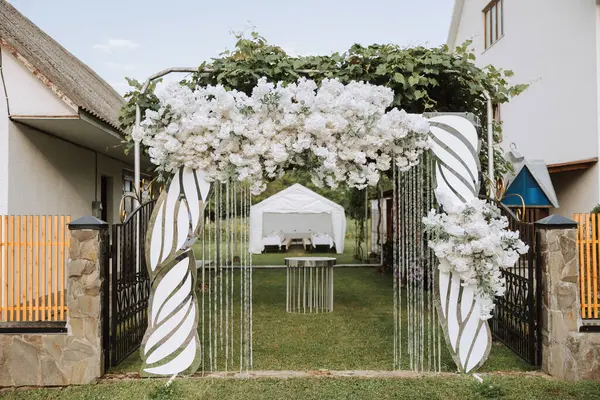 The photo zone at a wedding or birthday celebration is decorated with flowers and illuminated by natural light.