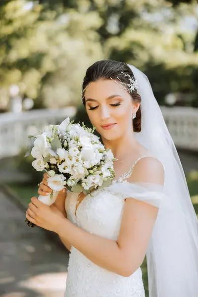 정도로 아름다운 드레스를 사랑스러운 신부는 꽃다발을 즐기고 냄새를 맡습니다 결혼식 — 스톡 사진