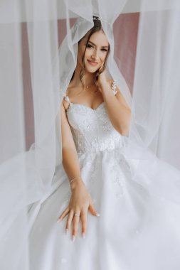 Beyaz gelinlik içinde duvak tutan genç bir gelin otel odasında esmer gelin portresi, düğünden önceki sabah..