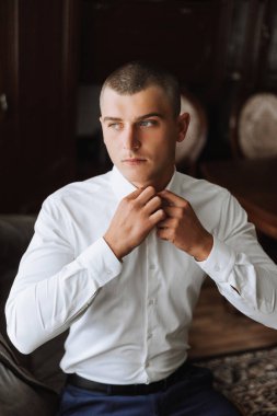 İş gömleği. Beyaz gömlekli bir adam düğmeleri bağlar. Genç politikacı, erkek tarzı, işadamı gömleği, erkek eli yakın, Amerikalı, Avrupalı işadamı