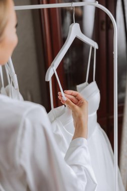 Odasında uzun peçeli, bornoz giymiş güzel bir gelin. Bir mankenin üzerinde gelinlik. Düğün töreninden önceki sabah gelin..