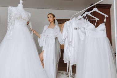 Odasında uzun peçeli, bornoz giymiş güzel bir gelin. Bir mankenin üzerinde gelinlik. Düğün töreninden önceki sabah gelin..