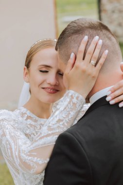 Gelin ve damat kucaklaşır. Gelin damadı nazikçe omuzlarından kucaklıyor. Güzel bir düğün çifti. Yeni evlilerin ilişkilerinde romantizm kavramı. Balayı.