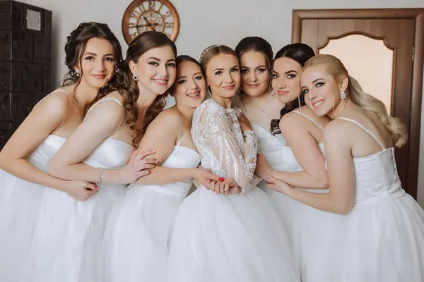 A beautiful bride and her bridesmaids are having fun in the morning. Wedding celebration. Happy girls at their best friend\'s wedding. A beautiful and elegant bride with her bridesmaids