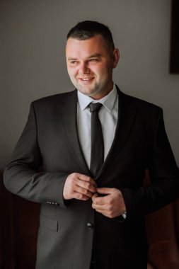 Düğünden önce damadın elleri ceketini bağlar. Takım elbiseli bir adamın yakın çekimi. İş adamı takım elbise giyer. Adam ceketinin düğmelerini bağlıyor..