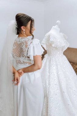 İnanılmaz güzel bir gelinin sabah hazırlığı. İçeride bir mankenin üzerinde duran gelinliğin yanında güzel bir bornoz giymiş bir kız. Gelinin düğün hazırlıkları..