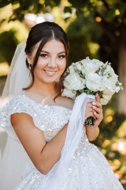 Portre. Elbise ve peçeli esmer bir gelin şık bir taçla buketle poz veriyor. Gümüş mücevherler. Güzel makyaj ve saç. Sonbahar düğünü. kutlama