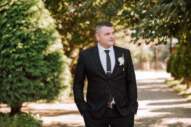 Bir sonbahar gününde zarif bir takım elbiseyle yakışıklı bir damadın portresi. Açık hava fotoğrafı. Takım elbiseli yakışıklı bir adam..