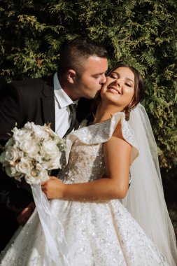 Genç bir gelin ve damat sonbahar güneşinin ışınlarında şefkatle kucaklaşır. Şefkatli ve güzel genç kız gelin. Bir adam sevgilisini öper. Güzel bir bahçenin arka planında