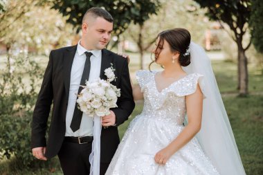 Sonbahar parkında yürüyüş yapan düğün çifti. Güzel beyaz elbiseli gelin. Aşk ve ilişki kavramı. Doğada damat ve gelin