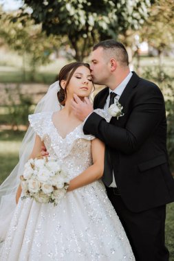 Genç bir gelin ve damat sonbahar güneşinin ışınlarında şefkatle kucaklaşır. Şefkatli ve güzel genç kız gelin. Bir adam sevgilisini öper. Güzel bir bahçenin arka planında