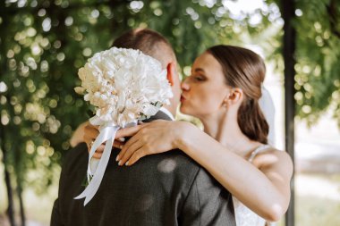 Şirin ve şık yeni evliler güzel bir bahçede sonbahar doğasının arka planına sarılıp gülümsüyorlar. İnanılmaz güzel genç bir gelin sevgilisini öper.