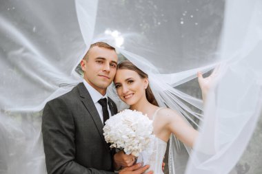 Onunla evlendiğim için çok mutluyum. Düğünlerinde duvak altında damadını kucaklayan şefkatli genç bir gelinin kırpılmış görüntüsü..