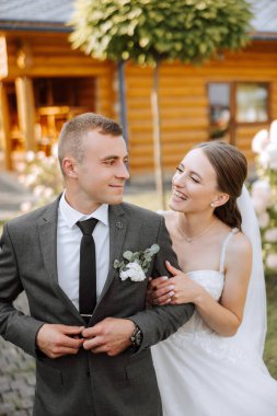 Güzel ve şık yeni evliler güzel bir bahçede sonbahar doğasının arka planına karşı sarılıp gülümsüyorlar. İnanılmaz güzel genç bir gelin, sevgili damadının omzuna yaslandı.