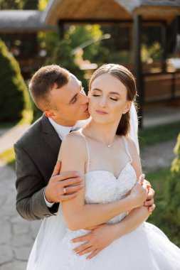 Genç bir gelin ve damat sonbahar güneşinin ışınlarında şefkatle kucaklaşır. Şefkatli ve güzel genç kız gelin. Bir adam sevgilisini öper. Güzel bir bahçenin arka planında