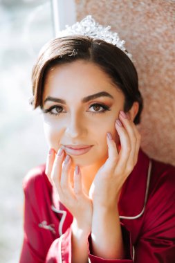 Lüks ve güzel bir gelinin, lüks bir otelde kırmızı pijamaları ve kafasında bir tacıyla, pencerenin kenarında durduğu sabah..