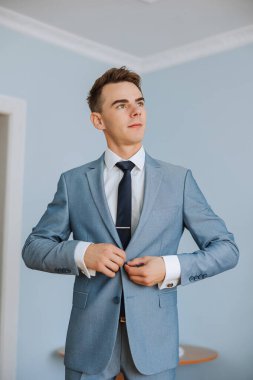 Düğünden önce damadın elleri ceketini bağlar. Takım elbiseli bir adamın yakın çekimi. İş adamı takım elbise giyer. Adam ceketinin düğmelerini bağlıyor..