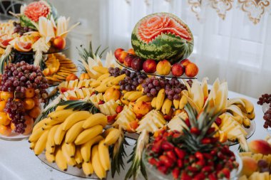 Meyve ve böğürtlen dolu bir ziyafet masası, bir sürü tatlı. Muz, üzüm, ananas. Tatil için meyve kompozisyonları.