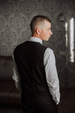 Beyaz takım elbiseli başarılı bir adamın arka portresi. Odada poz veriyor. Genç ve mutlu bir patron ya da CEO.