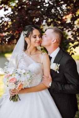 Genç bir gelin ve damat sonbahar güneşinin ışınlarında şefkatle kucaklaşır. Şefkatli ve güzel genç kız gelin. Bir adam sevgilisini öper. Güzel bir bahçenin arka planında