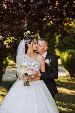 Genç bir gelin ve damat sonbahar güneşinin ışınlarında şefkatle kucaklaşır. Şefkatli ve güzel genç kız gelin. Bir adam sevgilisini öper. Güzel bir bahçenin arka planında