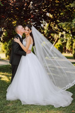 Genç bir gelin ve damat sonbahar güneşinin ışınlarında şefkatle kucaklaşır. Şefkatli ve güzel genç kız gelin. Bir adam sevgilisini öper. Güzel bir bahçenin arka planında