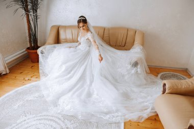 İnanılmaz güzel bir gelin yatak odasında bir yatakta oturur. Gelin sabahı. Parlak bir odadaki bir yatakta oturan güzel elbiseli muhteşem bir gelin. .