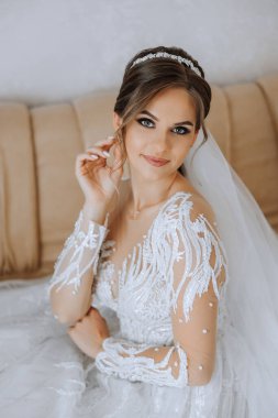 Evdeki düğün töreninden önce küpe takan genç ve güzel bir gelin. Beyaz gelinlikli bir gelin, sabahları odasına küpe takar..