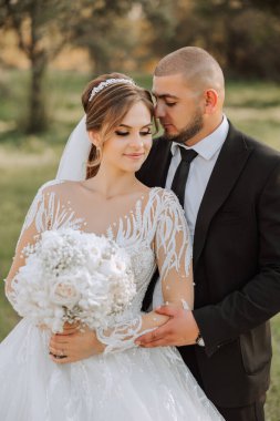 Genç bir gelin ve damat sonbahar güneşinin ışınlarında şefkatle kucaklaşır. Şefkatli ve güzel genç kız gelin. Bir adam sevgilisini öper. Güzel bir bahçenin arka planında