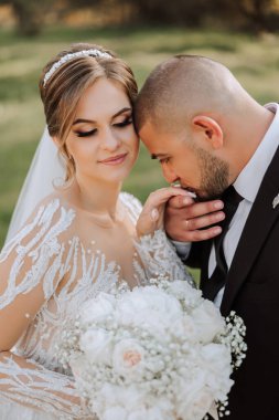 Damat gelinin elini öpüyor. Birbirine aşık bir çiftin düğün fotoğrafı. Genç ve yakışıklı bir adam karısının elini altın bir yüzükle öpüyor..