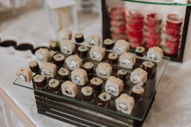 Yemek masasının arasındaki suşi barı. Çeşitli aperatifler, mezeler, deniz ürünleri ve düğün, Noel, iş dünyası, doğum günü partisi veya diğer etkinlikler için açık büfe olarak sergilenen pişirilmiş yemekler.
