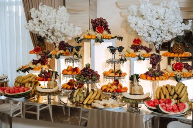 Meyve ve böğürtlen dolu bir ziyafet masası, bir sürü tatlı. Muz, üzüm, ananas. Tatil için meyve kompozisyonları.