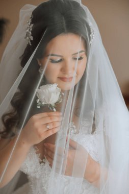 Beyaz gelinlik içinde duvak tutan genç bir gelin otel odasında esmer gelin portresi, düğünden önceki sabah..