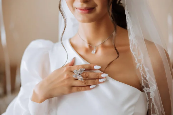 Close-up of an elegant diamond ring in the form of a butterfly on the finger of a woman with a modern manicure, sunlight. Love and wedding concept. Soft and selective focus.