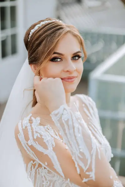 Wedding portrait. A brunette bride in a lace dress with long sleeves poses near a glass railing. Beautiful hair and makeup. Autumn. Daylight. celebration.